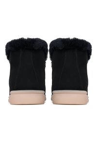 Svarta mockaankelboots med en mjuk svart pälskrage, ljusgula gummisulor och sömnadsdetaljer på sidorna.