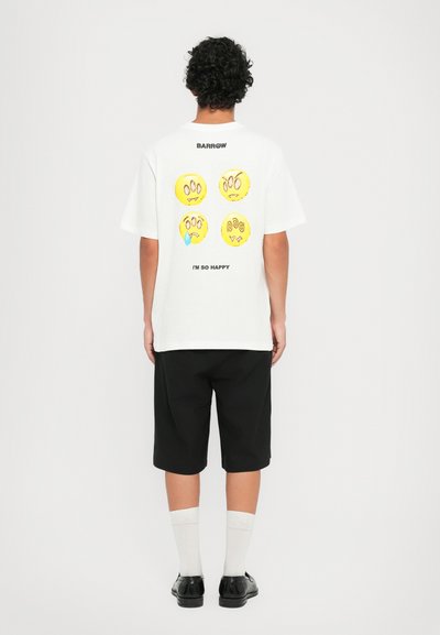 T-shirt in cotone bianco con quattro facce di cartoni animati colorate sul retro, con il testo "BARROW" e "SONO COSÌ FELICE" sotto i disegni.