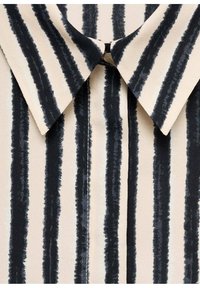 Gestreepte blouse van zachte stof, met gedurfde zwarte penseellijnen op een crème achtergrond en een klassiek puntig kraagontwerp.