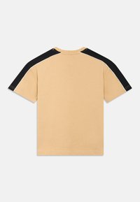 Κοντομάνικο t-shirt σε ανοιχτό μπεζ βαμβάκι με μαύρες πινελιές στα μανίκια και αντίθετες ραφές· κανονικός στρογγυλός λαιμός και άνετη εφαρμογή.