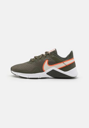Basket Nike vert olive avec logos accent orange et blanc, semelle blanche, design à lacets, et motif hexagonal texturé sur la tige.
