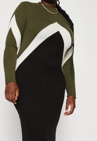 Abito a maniche lunghe in maglia con design a blocchi di colore nei toni verde oliva, bianco e nero; silhouette aderente con una texture liscia.