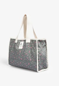 Bolso tote rectangular con estampado de leopardo gris y rosa, asas de tela blanca, ribete y un pequeño parche con una calavera y huesos cruzados.
