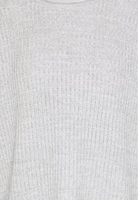 Pull gris clair en maille avec une texture côtelée, un col rond et une coupe ample. Le matériau semble doux et légèrement structuré.