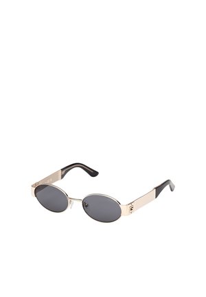 Sonnenbrille mit ovalen grauen Gläsern und einem goldenen Metallrahmen. Sie verfügt über schwarze Tempelakzente und dezente Markenkennzeichnung an der Seite. Nicht polarisierte Gläser.