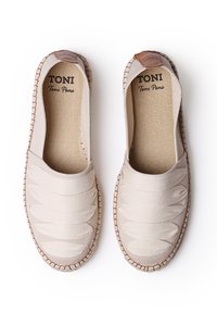 Espadrillas beige senza lacci con tomaia in tessuto texturizzato e strisce di tessuto sovrapposte, accentuate da un dettaglio in pelle marrone sul tallone e suola in juta.