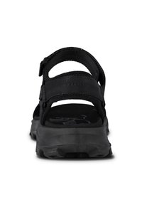 Mustat sandaalit, joissa on säädettävät remmit ja teksturoitu pohja. Varustettu kestävästä kumipohjasta ja pehmustetusta nilkatuesta mukavuutta varten.