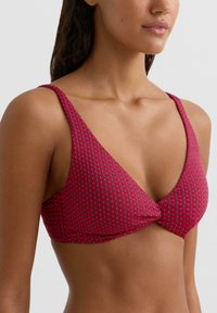 Czerwony top bikini z teksturowanym wzorem tkanym, wzorem w kształcie litery V, wąskimi ramiączkami i skręconym supełkiem na środku przodu.