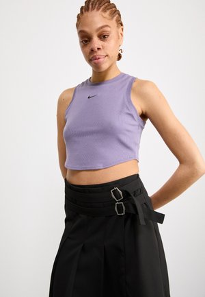 Top corto de color lila con textura acanalada y un logotipo de Nike negro, combinado con pantalones negros de cintura alta que tienen acentos de doble hebilla.