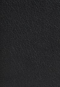 Superficie in pelle nera texturizzata con una finitura granulosa, caratterizzata da un colore uniforme e da leggere variazioni nella texture.