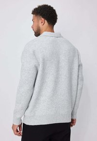Pull en laine gris à finition texturée, doté d'un col large et d'un ourlet côtelé. Le design arrière est simple avec une coupe décontractée.