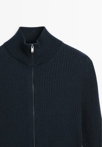 Dark navy zip-up sweater featuring a high ribbed collar, zip closure, and textured knit pattern.