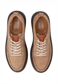 Beżowe zamszowe sneakersy z białymi sznurowadłami, brązowymi gumowymi podeszwami i brązowym skórzanym akcentem na języku. Płaski kształt, minimalne detale szycia.