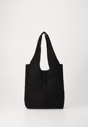 Black suede tote bag with wide handles and visible vertical stitching down the center, displayed against a plain light background.