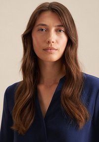 Blusa blu navy con scollatura a V. Tessuto liscio e maniche lunghe, caratterizzata da uno stile minimalista adatto a diverse occasioni.