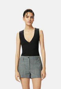 Bodysuit sin mangas negro con diseño de escote en V combinado con pantalones cortos de cuadros de talle alto en gris, azul y sutiles toques de naranja.