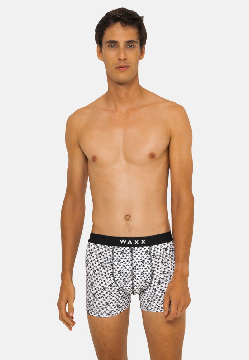 Boxers pour hommes avec une ceinture noire portant l'inscription "WAXX". Le corps est blanc avec un motif noir répété de petites formes. Tissu doux au toucher.