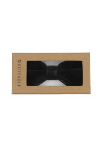 Zwarte fluwelen vlinderstrik gepresenteerd in een transparante doos met een kraftpapier ondergrond. De vlinderstrik heeft een centraal knoopdetail.