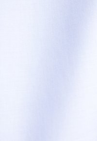 Witte textuurstof met zichtbaar diagonale weefpatroon en zachte plooien die subtiele schaduwen creëren.