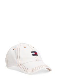 Hvid bomuldscap med syede detaljer, buet skygge og et mærke med "TOMMY JEANS" i sort, rød og blå. Seks ventilationshuller synlige.