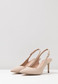 Talons aiguilles à brides arrière en daim nude avec un bout pointu et un talon aiguille de 3 pouces ; bride au niveau de la cheville réglable ; doublure intérieure lisse.
