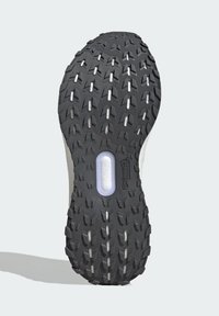 Semelle de sneaker en caoutchouc noir avec des rainures profondes et des motifs moulés ; présente une découpe de semelle intermédiaire révélant un matériau amortissant ; accents latéraux gris.