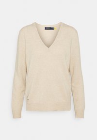 Beige V-ringad tröja i mjukt stickat material med långa ärmar och avslappnad passform. Ribbad manschetter och nederkant, med en liten logotypdetalj på sidan.