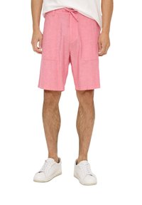 Roze, knielange shorts van lichtgewicht materiaal met een trekkoord in de taille en twee grote voorzakken. Gedragen met witte sneakers.