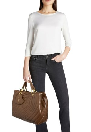 Borsa a mano in pelle marrone con motivo trapuntato a forma di cuore, ferrature dorate e targhetta rimovibile a forma di cuore. Texture morbida e forma strutturata.