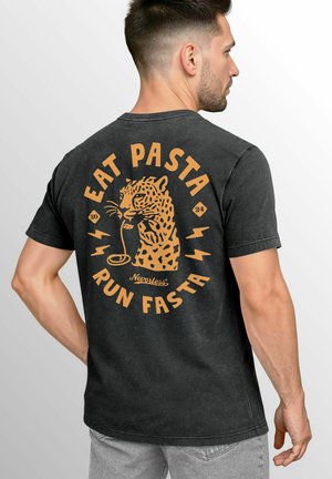Black cotton t-shirt featuring a central graphic of a leopard eating pasta, with orange text, lightning bolts, and a diamond-shaped accent.