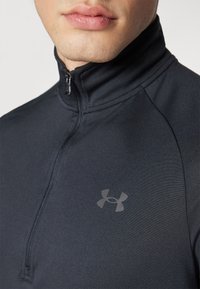 Czarna, sportowa bluza z długim rękawem, z półzamkiem i stójką. Z subtelnym szarym logo na lewej piersi oraz gładką fakturą.