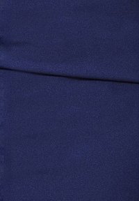 Granatowy materiał o gładkiej fakturze, z lekkim połyskiem. Zagięcia tworzą miękkie linie, wskazując na elastyczną, zwisającą jakość.