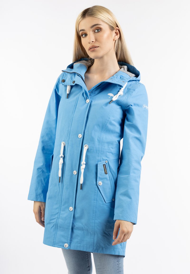 Chaqueta impermeable azul clara con capucha, cordones ajustables, dos bolsillos laterales y botones plateados. Textura suave, diseño casual.