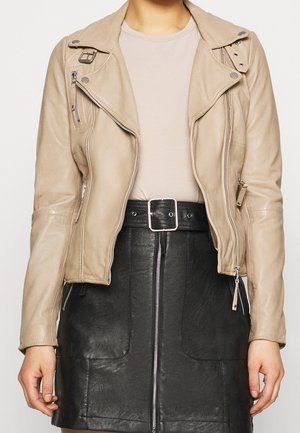 Beige læder bikerjakke med lynlåslommer, knapkrave og sølv hardware, parret med en sort læderskirt med frontlynlås.