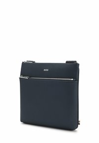Granatowa syntetyczna torba o gładkiej fakturze, z dwoma zamykanymi na zamek przegródkami i subtelnym oznaczeniem marki. Posiada elegancki, prostokątny kształt.
