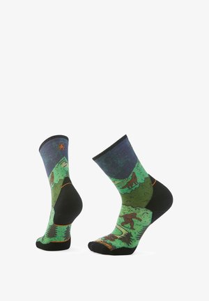 Kniesokken tot aan de knie met een zwarte onderkant; groen landschapspatroon met dieren, bomen en bergen; donkerblauwe boord.