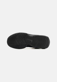 Sole di scarpa sportiva nera con gomma testurizzata, caratterizzata da scanalature profonde e un logo stilizzato. Design elegante con pattern stampati per migliorare la presa.