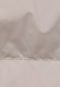 Helles beiges Gewebe mit glatter Textur, das über einen subtilen Glanz verfügt. Genähter Saum zeigt eine feine, gleichmäßige Naht am unteren Ende.