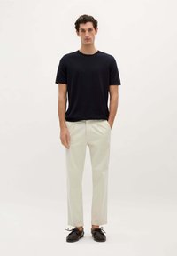 Marineblå kortærmet t-shirt, lys beige bukser og mørke sko. Glat stof, afslappet pasform og minimalistisk design uden synlige mønstre.