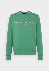 Groene longsleeve crewneck sweatshirt met "Tommy Hilfiger Est. 1985" en het rode, witte en blauwe logo van het merk op de borst.