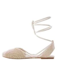 Beige tasapohjaiset kengät, joissa on tekstuurilla valmistettu virkkausosa edessä ja sileä takaosa. Ominaisuuksiin kuuluvat ohuet, ristikkäin menevät nilkkaremmit ja tasapohja.