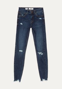 Vaqueros skinny de tiro bajo en azul oscuro con parches desgastados en los muslos y las rodillas, cierre de botón y dobladillos deshilachados.