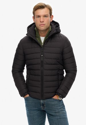 Chaqueta acolchada negra con diseño en acolchado, cierre de cremallera en la parte delantera y capucha ajustable, combinada con una capa interior de punto verde.