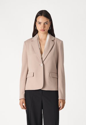 Blazer in light beige fabric with a lapel collar, single button closure, and two front pockets; tailored fit, minimal seams, and smooth texture.