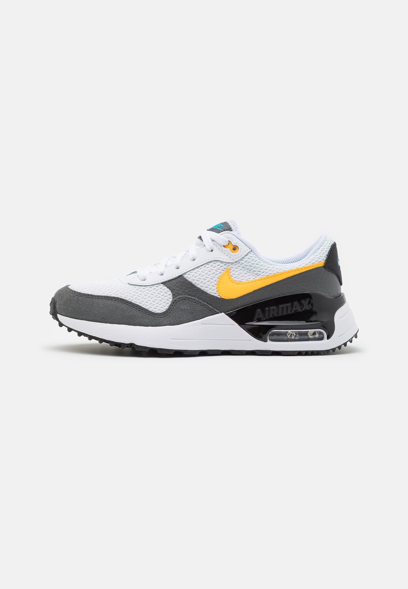 Sneaker bianca con inserti in suede grigio e suola in gomma nera, caratterizzata da uno swoosh giallo di Nike, tomaia in mesh e un'unità Air visibile nel tallone.