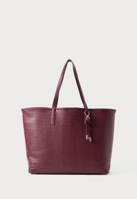 Burgundy tote bag made of textured material, featuring two long handles, a zip top closure, and a decorative tassel accent.