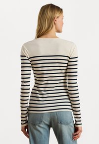 Maglione a maniche lunghe a righe in crema e blu navy, con righe orizzontali e scollo rotondo. Design morbido e aderente con polsini a coste.
