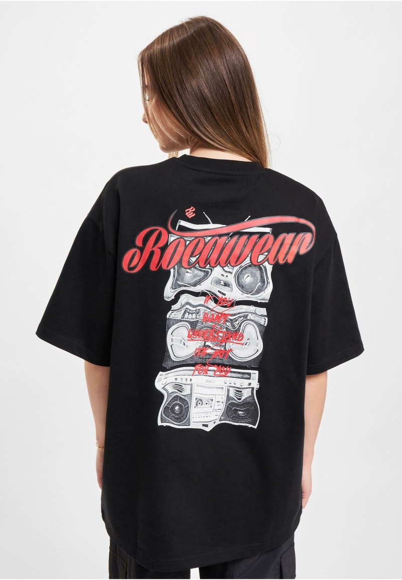 Svart oversized t-skjorte med grafisk trykk av stablede boombokser i hvitt og rødt, med "Rocawear"-tekst over i fet rødt skrift.