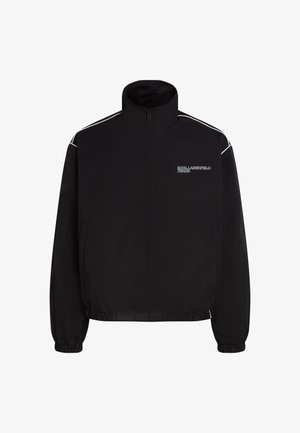 Zwarte zip-up jas van lichtgewicht stof, met een hoge kraag, elastische manchetten en witte accentstrepen op de schouders.