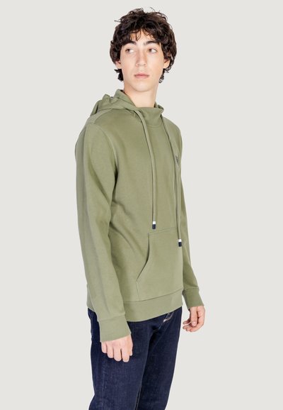 Hoodie vert olive en matière douce, avec une poche avant, des cordons de serrage ajustables et des poignets côtelés, associé à un jean foncé.